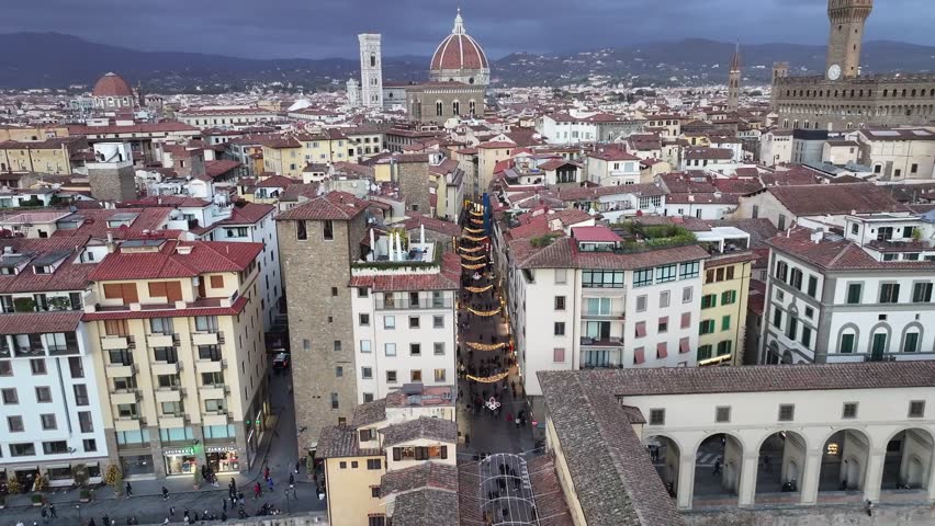 Cinematic push-in drone shot over historic Florence at twilight, showcasing the Duomo cathedral and narrow streets decorated with Christmas lights.