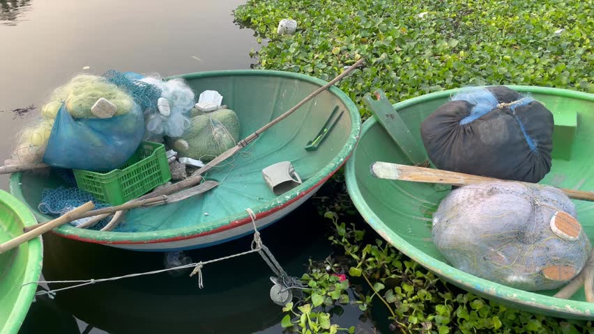 Fishing Nets and Baskets on coracle boat on Water Plants Near Pond