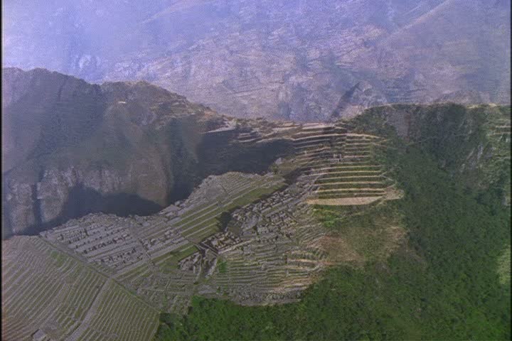 Aerial shot of Machu Picchu in the Andes Mountains, Peru, camera pushes in slightly to ruins.