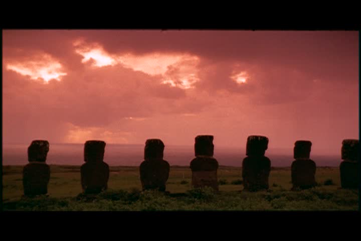 MS row of moai in silhouette against a pink sunset sky on Easter Island, Chile.