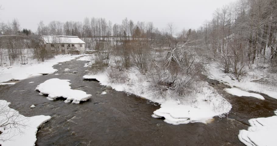 Vantaankoski rapids during the winter. The white building visible on the of the river is the Vantaankoski old mill in cloudy winter weather, Vantaa, Finland, Europe.