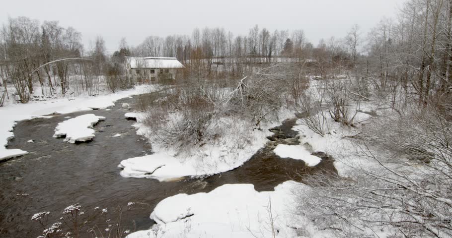 Vantaankoski rapids during the winter. The white building visible on the of the river is the Vantaankoski old mill in cloudy winter weather, Vantaa, Finland, Europe.