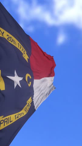 North Carolina State Flag Waving Against Bright Blue Sky Background