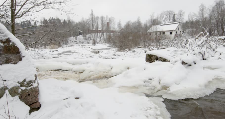 Vantaankoski rapids during the winter. The white building visible on the of the river is the Vantaankoski old mill in cloudy winter weather, Vantaa, Finland, Europe.