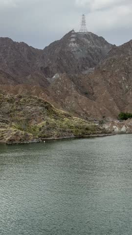 A scenic lake video featuring calm water, rugged brown mountains, and small paddle boats drifting across the water.