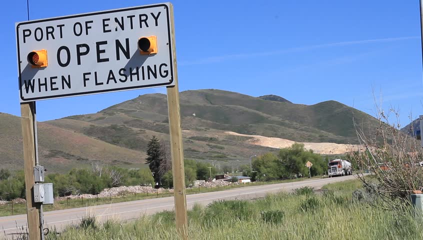 A flashing port of entry sign on the side of the road.
