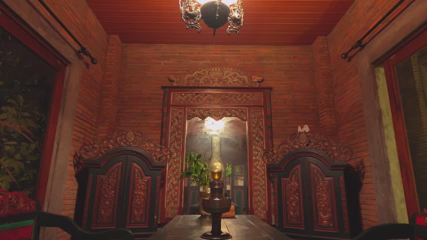 A perfectly framed shot of a private dining room featuring intricately carved green and gold wooden cabinets, a central table, and a vintage hanging lamp.