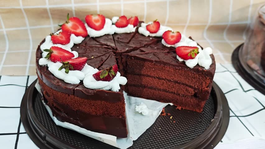 Slice of decadent chocolate cake with fresh strawberries and whipped cream.