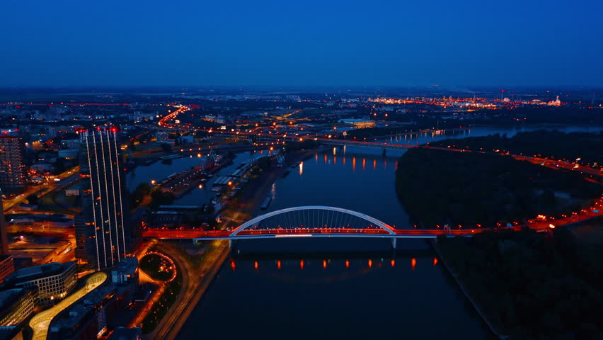 Beautifully illuminated roads of Bratislava, Slovakia. Drone flight approaching the Appolo Bridge over the Danube at night.