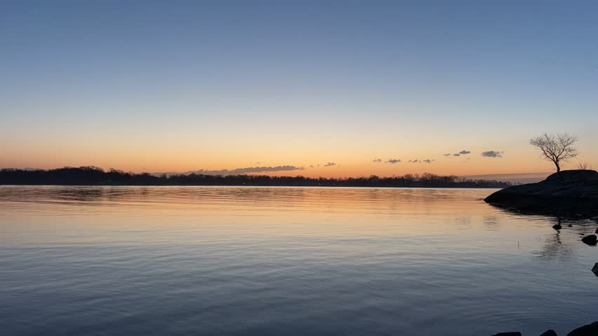 Stunning Sunset over a Calm Dark Lake with Silhouetted Trees on the Horizon