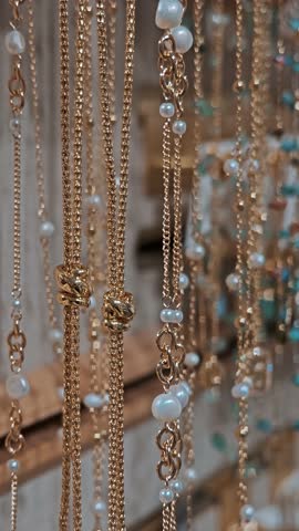 Thin silver and gold chains neatly hung on store display. Concept of jewelry retail trade.