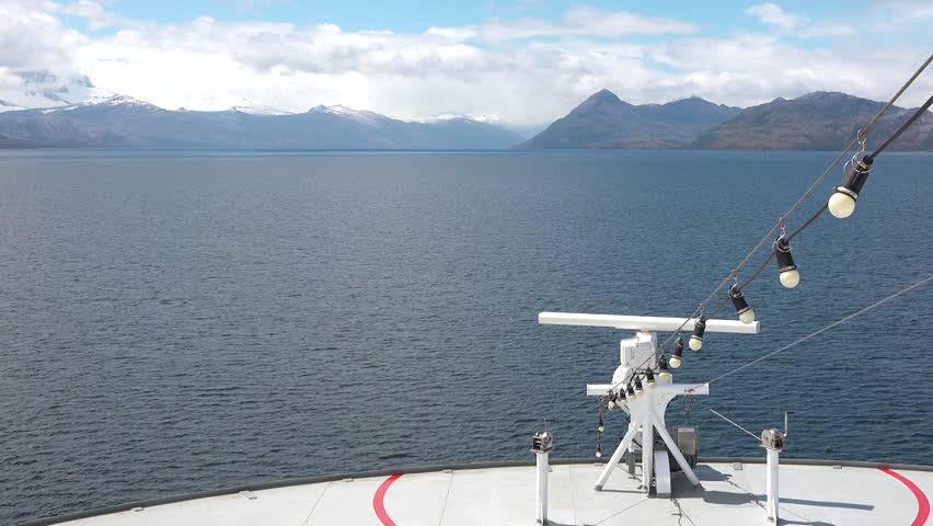 A ship navigates icy waters in Antarctica, with stunning views of snow-covered mountains and ice formations. The time is around noon, giving a clear look at the landscape.
