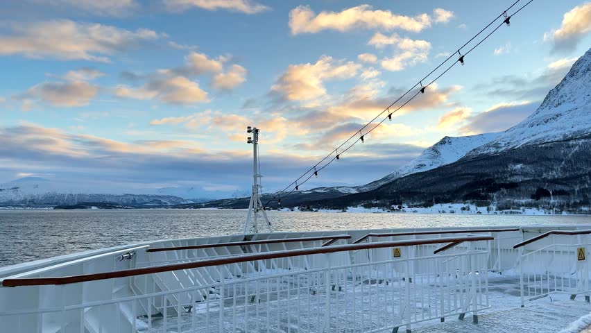 A ship navigates icy waters in Antarctica, with stunning views of snow-covered mountains and ice formations. The time is around noon, giving a clear look at the landscape.