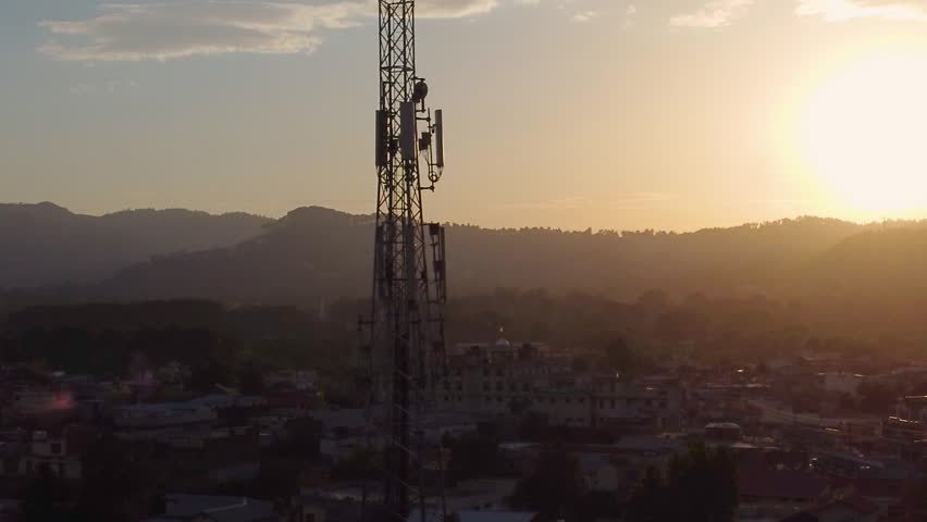 Sun Setting Behind Telecommunication Tower in Urban Landscape