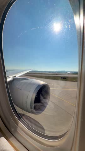 View from an airplane window during takeoff at Zurich Airport on a bright sunny day, runway and landscape visible below.