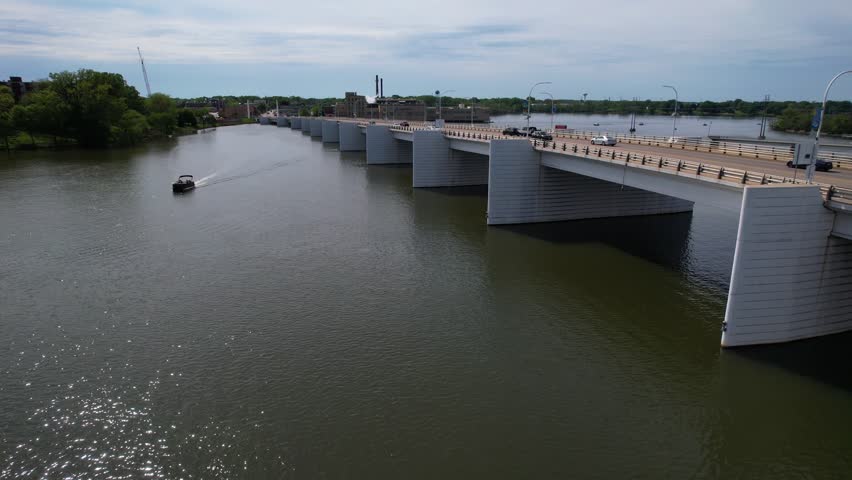 Aerial of DePere Wisconsin on the Fox River during summer.  Low drone shot over river with pontoon boat and bridge.