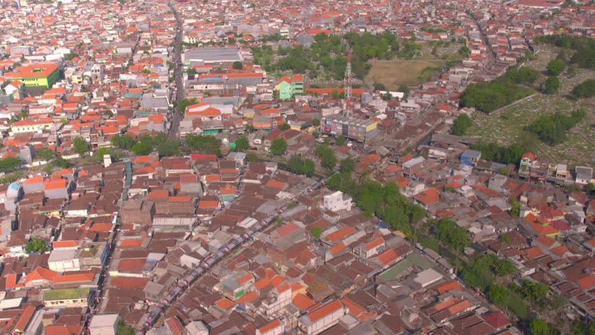 Logistics and Transportation in Java, Indonesia: An industrial-themed aerial photograph of a fuel tanker train traveling along multiple tracks, highlighting the intersection of modern logistics and traditional urban development in Surabaya