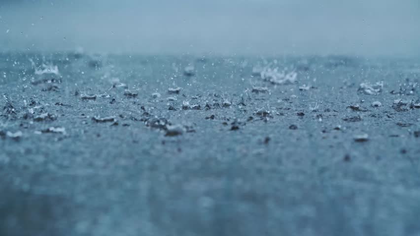 Cinematic close up rain falling on ground with strong splashes moody background