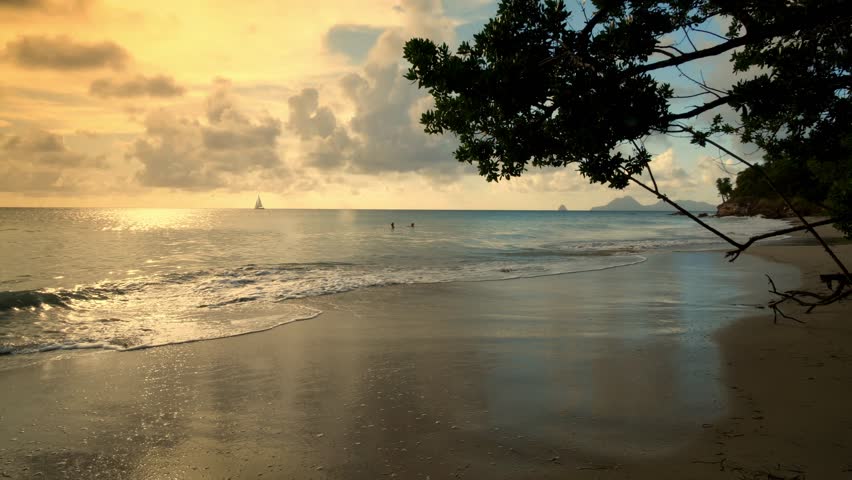 Sunset over the ocean with gentle waves hitting the sandy shore in Saint Martin Martinique. Wide angle shot.