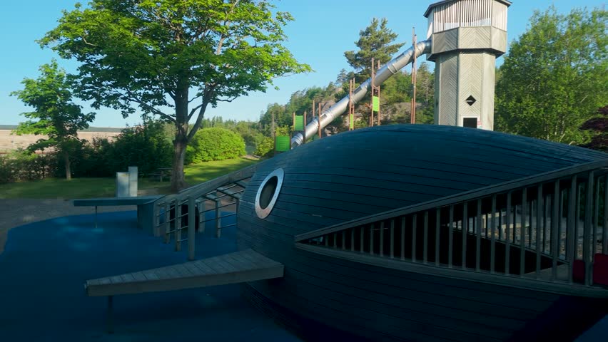 Low drone shot of Vattenkraftens Lekpark adventure playground in Trollhättan Sweden featuring whale climbing structure and tall tower slide