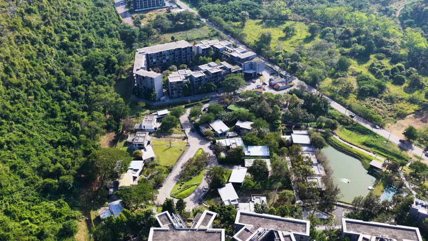 Drone shot reveals a modern resort complex surrounded by lush green mountains and tropical forests