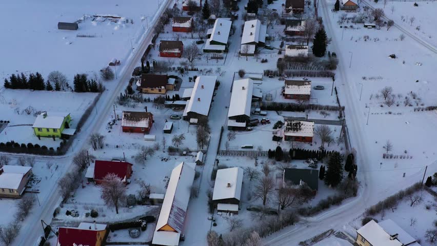 Winter settlement from above with snow covered houses and roads in rural village, aerial view with snowfall