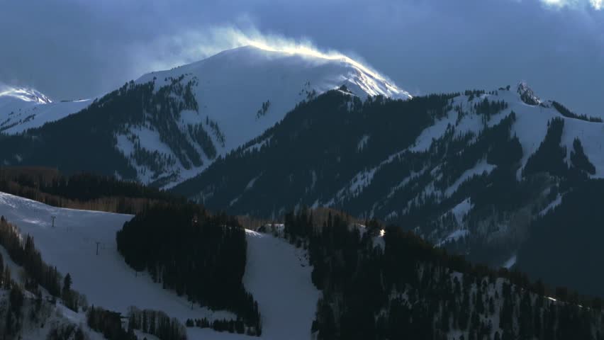 Aspen Highlands Bowl blowing snow Aspen Mountain AJAX Ski resort Pyramid Peak Maroon Bells Wilderness aerial drone sunset dark clouds ski trail runs Rocky Mountains peaks chairlift gondola upwards