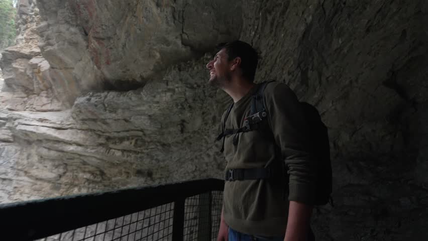 Enthusiastic man with a backpack discovering the impressive waterfall in Johnston Canyon in Banff national park