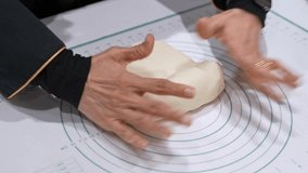 Close-up of hands kneading bread dough on a pastry mat indoors, showing home baking preparation, soft dough texture, and manual food making on a kitchen work surface. - Powered by Shutterstock - Get 15% off with code: PIKWIZARD15