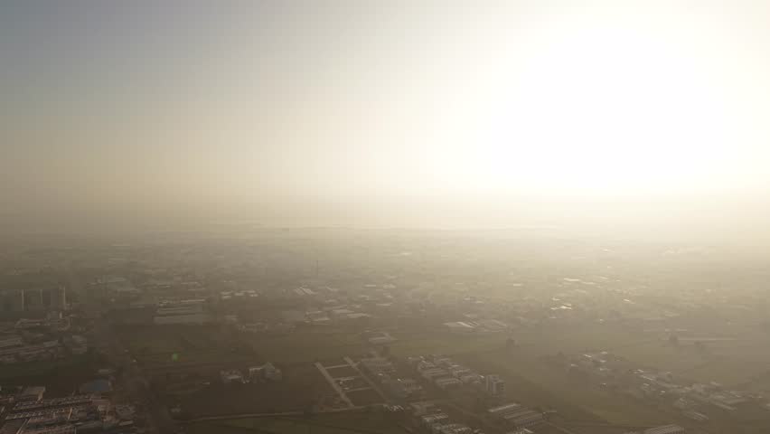 A sprawling industrial city shrouded in a thick, monochromatic layer of smog and morning mist.