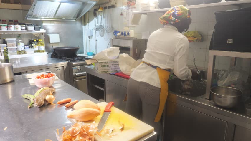 A skilled chef in a professional kitchen meticulously washes and prepares fresh ingredients for authentic African cuisine