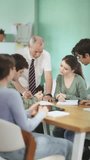 Elderly male professor talks to group of young students sitting at table and discussing assignment - Powered by Shutterstock - Get 15% off with code: PIKWIZARD15