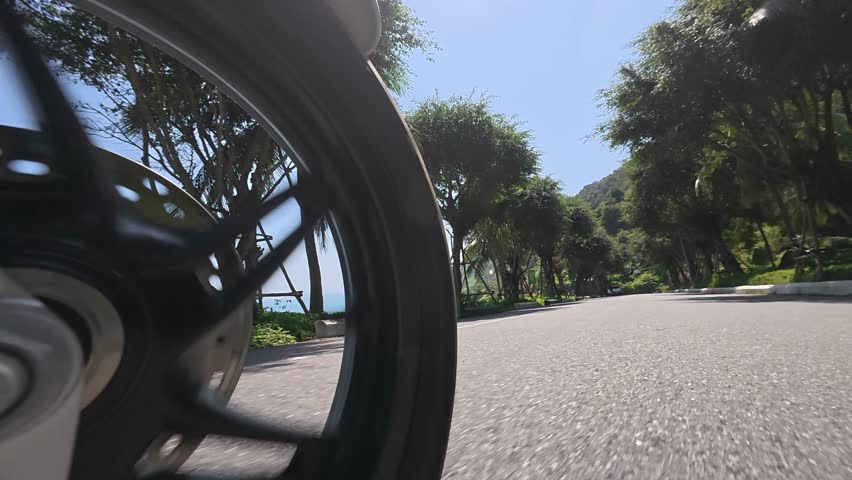 Low angle view of motorcycle wheel riding on sunny road