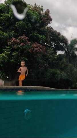 Boy swims in pool and makes splashes. Swimming aids help children learn to swim. Fun training for children in the sport aquatic school