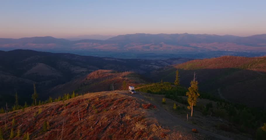Mountain ridge at dusk overlooking Missoula Montana valley, medium aerial approach over truck camper
