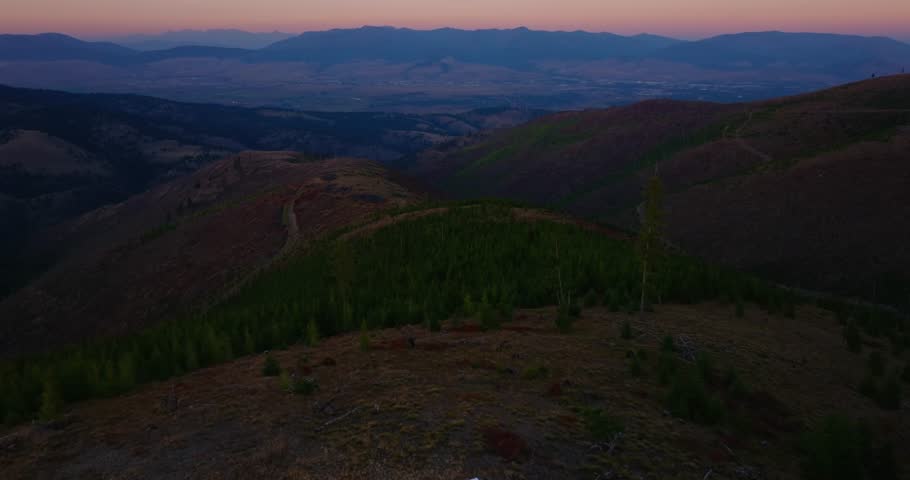 Dusk of camper van overlooking Missoula Montana mountains, aerial flyover pullback