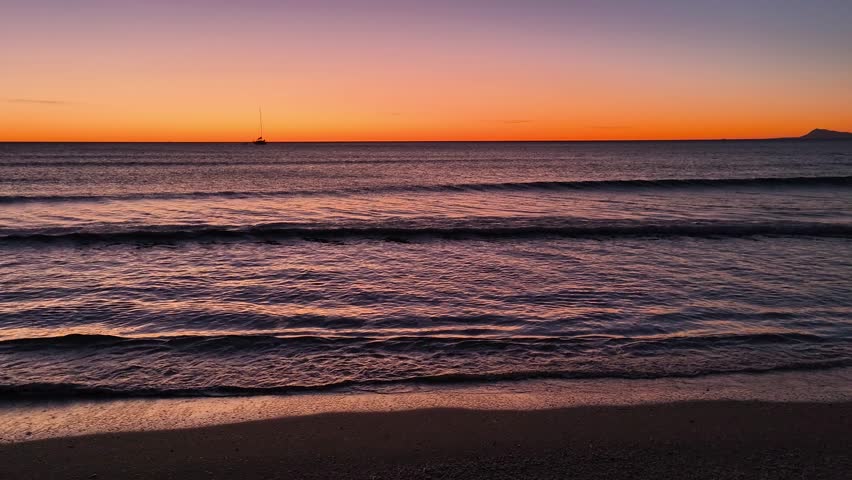 Red Sunrise Over Calm Sea with Sailboat Silhouette on Horizon