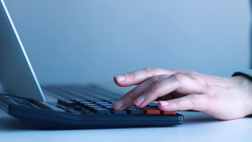 Working on a laptop with digital money management tools at home in the evening near a desk with various items.