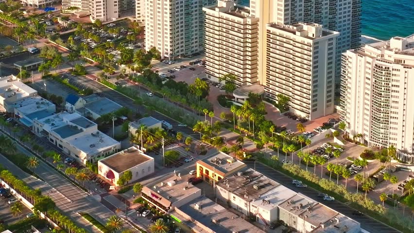 Buildings and streets in Miami. Cars line the roads, and many trees are visible. The image shows a busy urban area close to the coast during daylight.