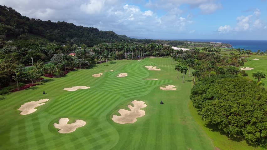 Perfectly manicured green fairway and sand bunkers on a luxury golf course in Rio San Juan, Dominican Republic. Aerial forward