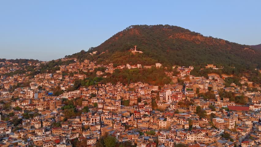 Aerial view dolly in of the Casahuates neighborhood on the slopes of Atache Hill with the monument to Christ the King in Taxco, Guerrero State, Mexico