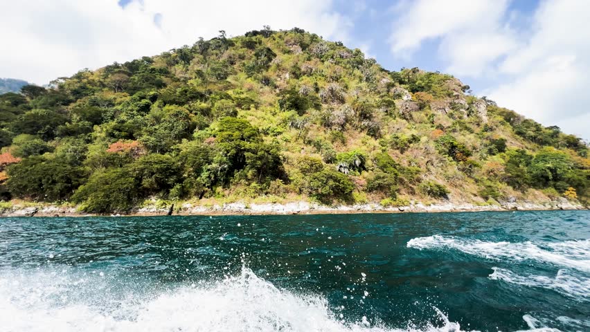 A boat speeds along the coastline of Lake Atitlán in Guatemala.