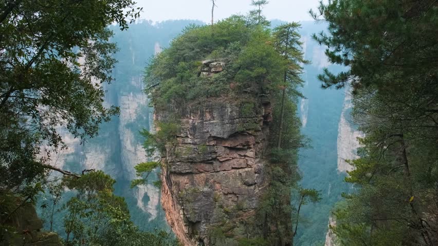 Vertical quartz sandstone rock pillars rising through mist in Yuanjiajie scenic area of Zhangjiajie National Forest Park landscape, Hunan, China. Travel and tourism landmark in Asia