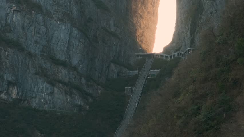 Natural stone arch with long staircase between towering cliffs at sunrise.in Tianmen Mountain National Forest Park, Zhangjiajie, Hunan, China. Tianmenshan cave with 999 steps