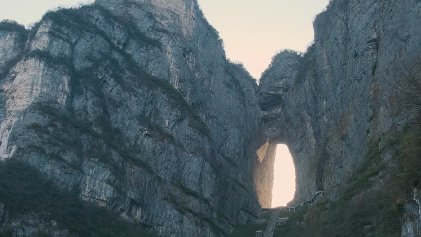 Heaven gate stone arch glowing at sunrise with steep staircase between towering cliffs at sunrise.in Tianmen Mountain National Park, Zhangjiajie, Hunan, China. Tianmen cave with 999 steps
