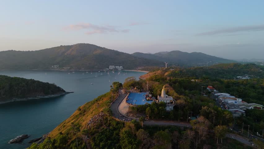 Expansive view from above Promthep Cape showcasing the curving coastline, calm Andaman Sea, and distant islands at sunset in Phuket Thailand