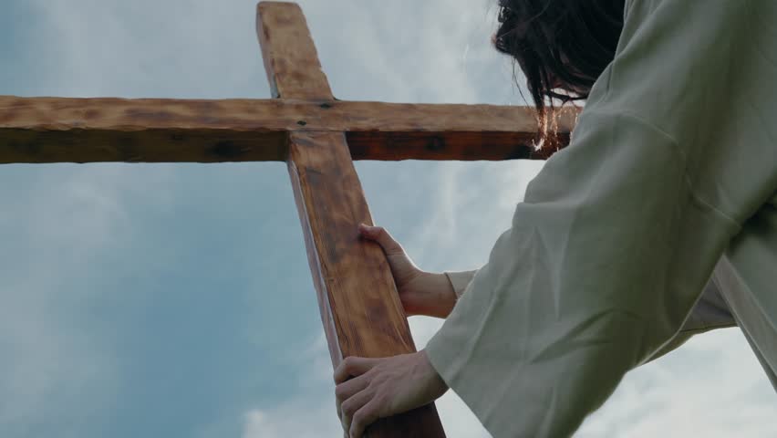 Jesus holding wooden crucifixion cross and contemplating the journey in slow motion Easter