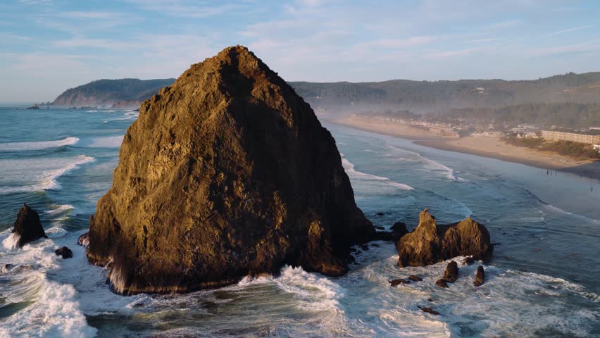Scenic aerial of Cannon Beach with tide pools and iconic rock formations. Ideal for stock footage, travel, or documentary use.