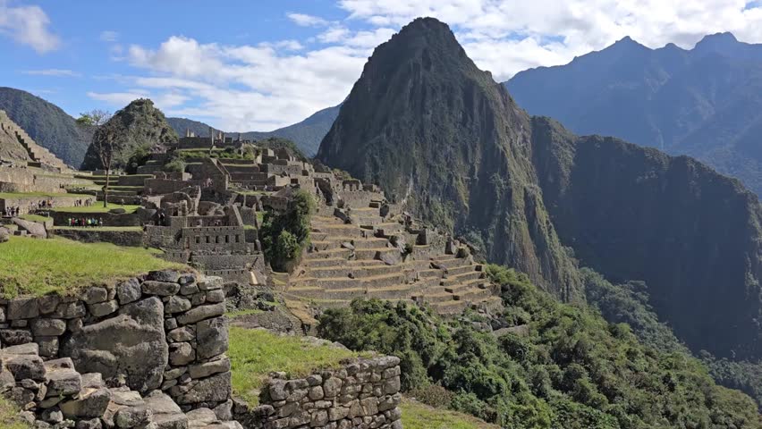 Machu Picchu, Peru - 26 June 2024. View over the Urubamba Valley with layered mountain ridges, dense vegetation, and strong sunlight creating contrast across the slopes.