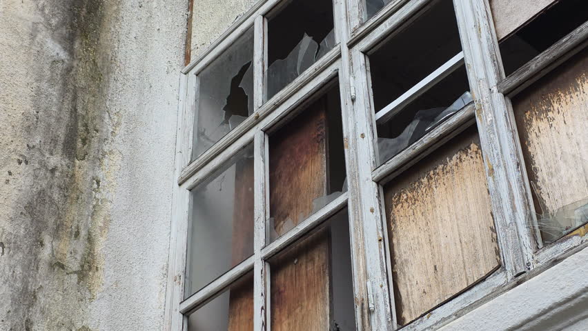 Derelict building with weathered walls and broken windows showing decay and abandonment in an old industrial factory